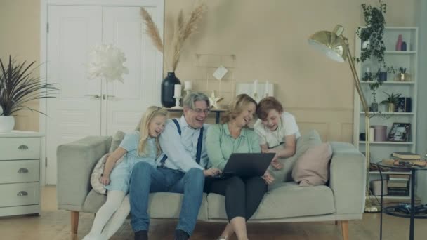 Grandparents and their grandkids are resting at home with a laptop — Stock Video