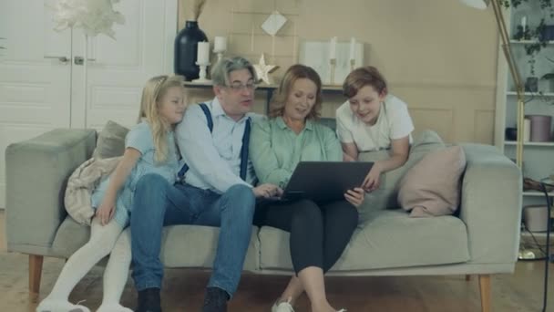 孩子们和他们的祖父母一边笑一边用笔记本电脑 — 图库视频影像