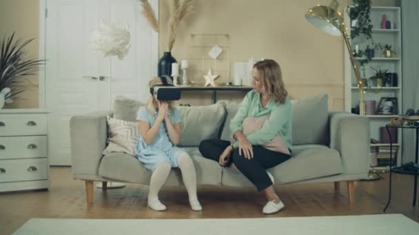 Бабушка наблюдает за внучкой в VR-очках — стоковое видео