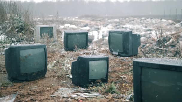 Viele kaputte Fernseher im Winter auf einer Mülldeponie. — Stockvideo