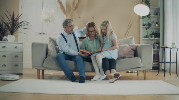 Os avós estão lendo um livro com uma menina — Vídeo de Stock