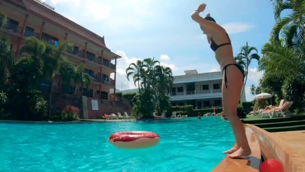 Resort zwembad en een dame duiken met een drijvende ring — Stockvideo