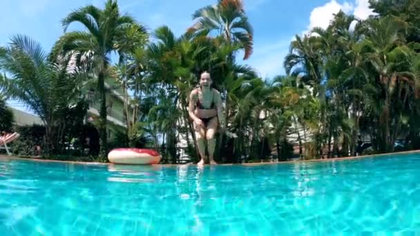 젊은 여자가 물장구를 치며 수영장으로 뛰어 든다 — 비디오