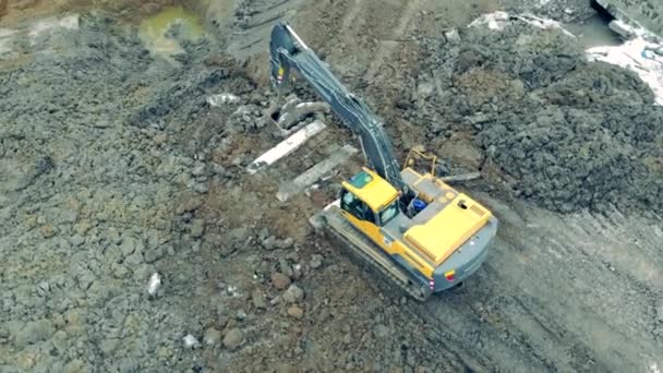 Gelber Baubagger bewegt schwere Steine in einem Steinbruch. — Stockvideo