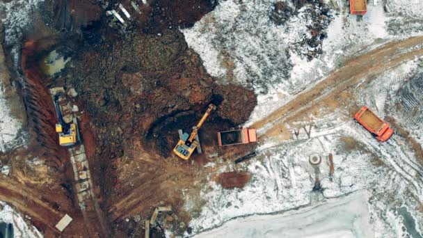 Aerial view from above of a construction site with excavators and trucks working. — Stock Video