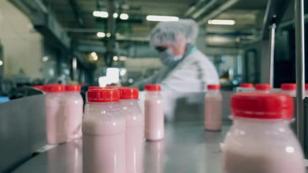 Flessen met yoghurt op een transportband in een fabriek. — Stockvideo