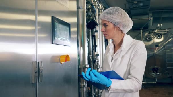 Kvinnlig fabriksarbetare kontrollerar industriell utrustning, fabriksmaskin på en mejerifabrik. — Stockvideo