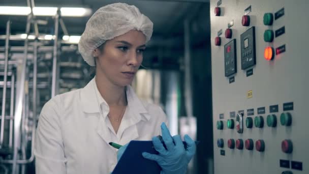 Γυναίκα εργάτης εργοστασίου ελέγχει μια μηχανή σε ένα εργοστάσιο γαλακτοκομικών προϊόντων. — Αρχείο Βίντεο
