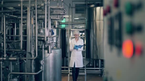 Een vrouw loopt een fabriek binnen en controleert machines.. — Stockvideo