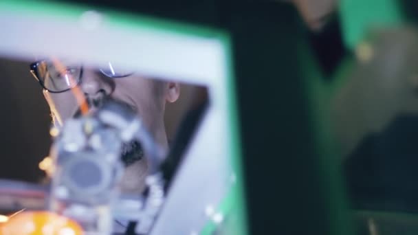 Een werknemer controleert 3D-printer met een vaas. — Stockvideo