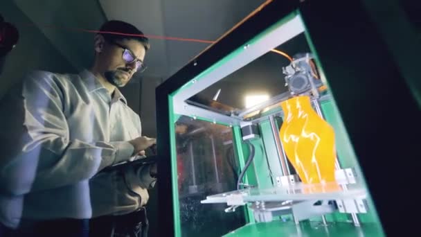 Человек управляет печатными машинами с помощью ваз. Профессиональный промышленный дизайнер создает 3D печатную продукцию в дизайнерском агентстве . — стоковое видео