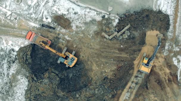 Industriële tractoren die werken met zand en stenen in een steengroeve. Bovenaanzicht vanuit de lucht van een bouwplaats met graafmachines en vrachtwagens aan het werk. — Stockvideo