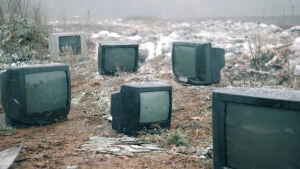 Broken TVs at the landfill site under falling snow — ストック動画