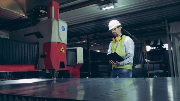 Mannelijke werknemer observeert een lasersnijder die metaal verwerkt — Stockvideo