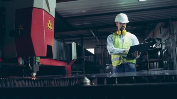Промышленный лазер делает надрезы на металле под контролем рабочих — стоковое видео