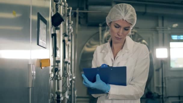 Lady specialist, engineer is writing down info from plant equipment — Stock Video