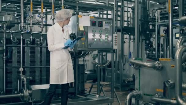 Unidade de fábrica moderna e uma funcionária a inspeccioná-lo — Vídeo de Stock