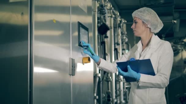 Kvinnlig expert reglerar inställningar av fabriksutrustning — Stockvideo