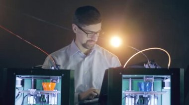 3D yazıcılar dizüstü bilgisayarı olan bir erkek uzman tarafından çalıştırılıyor.