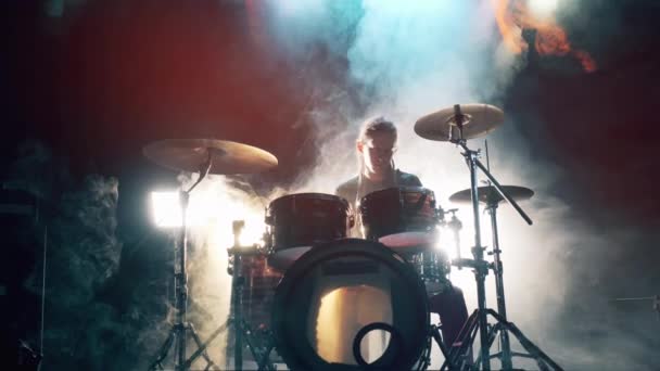 Музикант грає на барабанах у темній хмарній студії. Чоловік барабанщик грає на барабанах у диму . — стокове відео