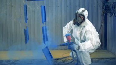 Uzman boya fabrikasında metal parçaları boyamak için sprey tabanca kullanıyor. Metal bir parçanın profesyonel el spreyi resmi..
