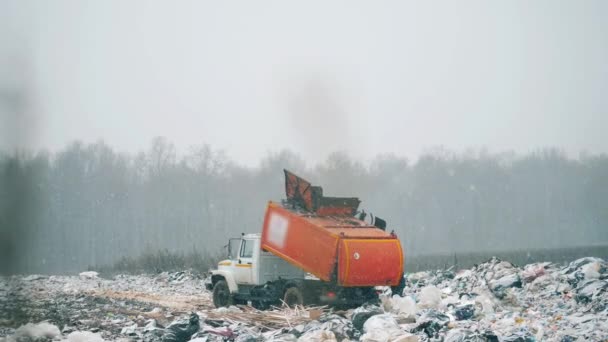 Oranje truck aan het werk met afval op een stortplaats. — Stockvideo