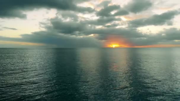 Słońce zachodzi do morza, które jest wystrzeliwane z góry. — Wideo stockowe
