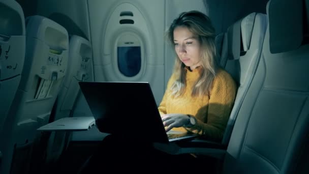 A woman is using a laptop on the airplane. Female passenger working inside of an airplane. — 비디오