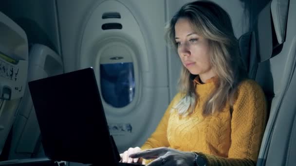 Gorgeous lady is operating a laptop on the plane at night — 비디오