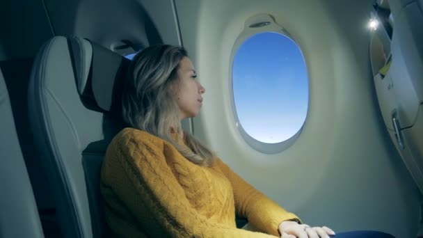Bir kadın uçak camından bakıyor. Uçakta otururken dizüstü bilgisayar kullanan kız