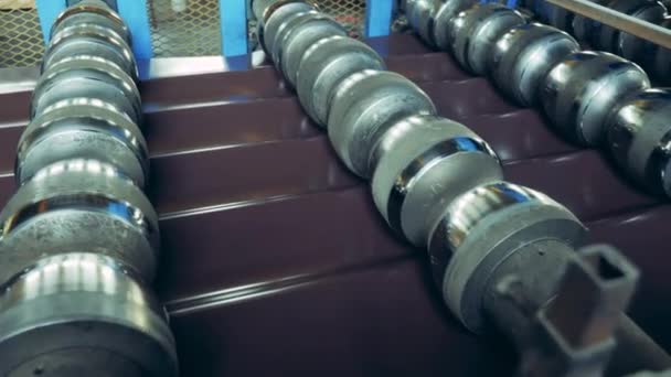 Rolling conveyor is processing metal shingles. Bending industrial equipment working with metal. — Stockvideo
