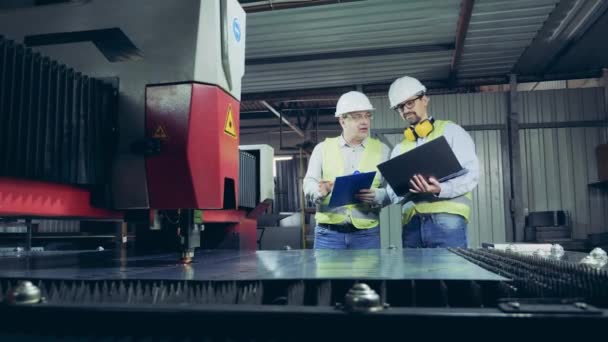 Mechanismus řezání laserem sledují dva inspektoři. — Stock video