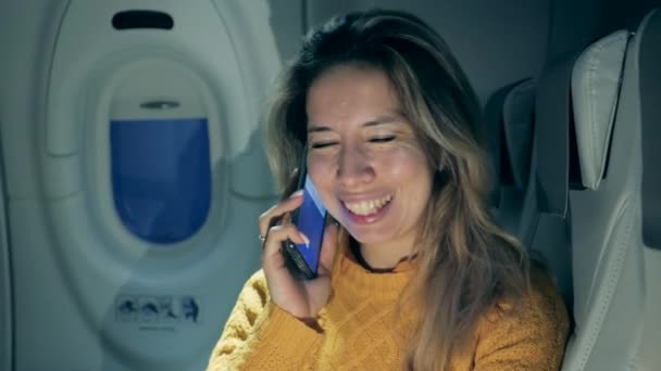 Великолепная женщина улыбается, разговаривая по телефону в самолете — стоковое видео