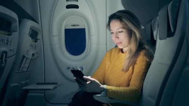 Una mujer está usando su teléfono inteligente mientras está en el avión — Vídeo de stock