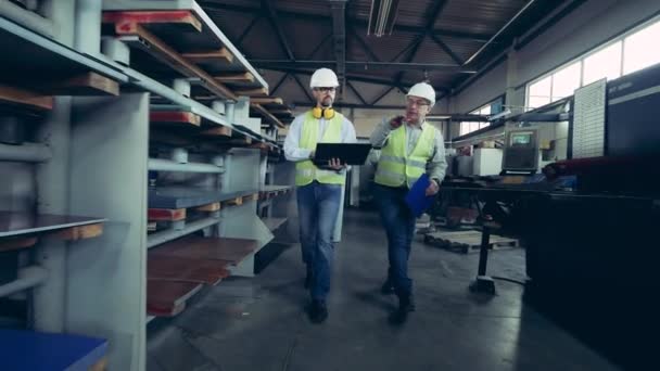 Δύο τεχνικοί περπατούν κατά μήκος του εργοστασίου υλικών στέγης. — Αρχείο Βίντεο