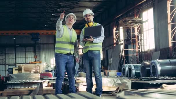 Dos técnicos están examinando una unidad de fábrica con materiales para techos — Vídeo de stock