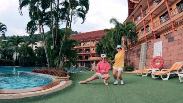 Två flickor dansar nära poolen. — Stockvideo