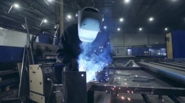 Erkek kaynakçı bir atölyede metalle çalışıyor. Yavaş çekim.