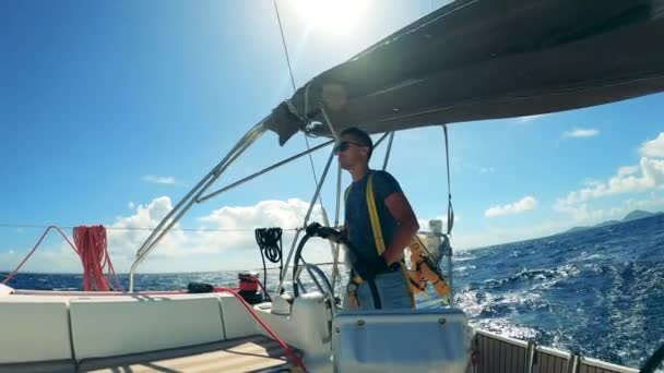 Zijaanzicht van een man op een jacht met een wiel. Jonge mannelijke schipper genieten van jacht vakantie. — Stockvideo