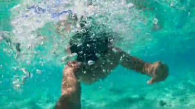 A man is diving in the sea and filming himself