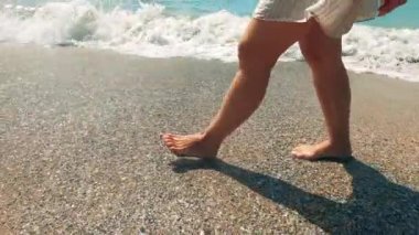 Seashore with waves and a woman walking along it