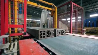 Uzun tuğlalar endüstriyel mekanizma tarafından kesiliyor.