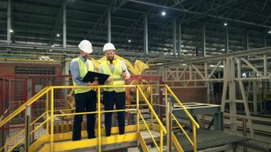 Bilgisayarlı iki mühendis bir fabrikayı inceliyor.