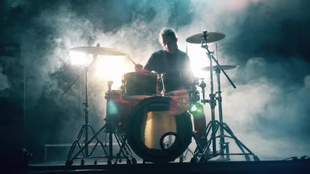 Профессиональный барабанщик играет на барабанах в студии, наполненной дымом — стоковое видео