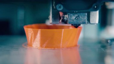 3D yazıcı turuncu bir nesne üretiyor. 3D baskı laboratuvarında çalışan 3D yazıcı.