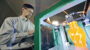 An expert is looking at a 3D-printing machine at work