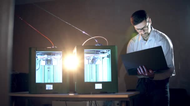 Dos impresoras 3D están trabajando bajo la supervisión de un experto masculino — Vídeos de Stock