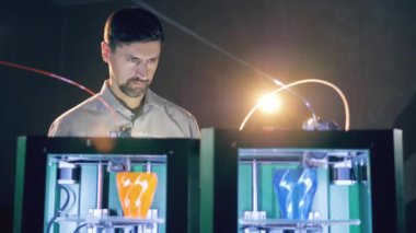 Male technician is watching 3D-printers intensely