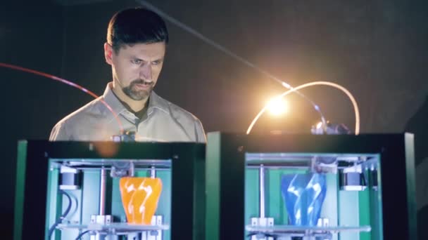 Техник-мужчина интенсивно смотрит 3D-принтеры — стоковое видео