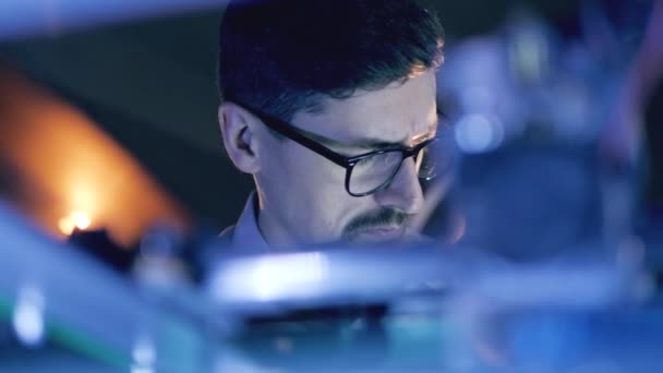 Człowiek pracujący z drukarką 3D w drukarni 3D. Mężczyzna specjalista w okularach obserwuje mechanizm pracy — Wideo stockowe